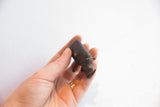 Handmade vintage rhino figurine with dark patina held to show its scale.