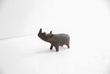 Side profile of a handmade African rhino figurine with a dark, time-worn patina.