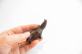 A hand holding the dark patina rhino figurine, showing its upward-tilted profile and scale.
