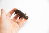 A hand holds the small dark patina rhino figurine, showing its collectible size.