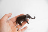 Vintage dark patina elephant figurine held in hand to demonstrate scale.
