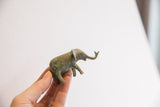 Small African elephant figurine held to show its scale and oxidized green finish.
