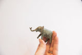 Collector's vintage African elephant figurine held, revealing textured green patina.