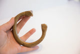 Antique African cuff bracelet held to show its substantial size and ridged surface.