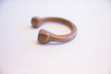 Close-up of hand-etched geometric designs on the flared base of the antique copper cuff.