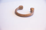 Profile of an antique African copper cuff showing its curved shape and geometric etchings.