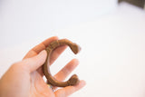 Small antique African copper cuff bracelet with geometric patterns held in hand.