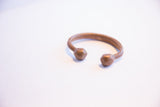Angled profile of an antique African copper cuff with smooth, knobbed ends.