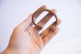 Antique African copper cuff bracelet held in a hand to show scale and form.