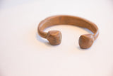 A profile view of the antique copper cuff's open ends and hand-worked patina.