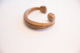 Angled view of the antique copper cuff's open form and faceted ends.