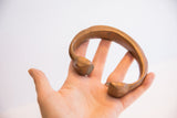 Hand holding an antique copper snake cuff, showing its open form and aged patina.