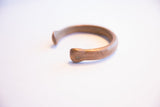 Side view showing the open C-shape of the antique copper snake bracelet.