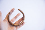 Antique copper cuff bracelet held in hand to show scale and form.