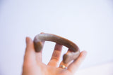 A view of the antique copper cuff's substantial thickness and smooth, curved shape.