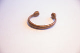 Angled view of an antique African snake cuff showing its rich, warm metallic patina.