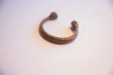 The curved form and warm, aged patina of an antique African snake cuff bracelet.