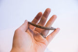 Vintage African cuff bracelet held in hand, showing its scale and simple, curved form.