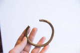 Aged metal African cuff bracelet held to show its simple form and scale.