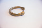Close-up of hand-stamped markings on the rounded end of the bronze snake cuff.