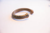 The curved profile and textured surface of a handmade antique African snake cuff bracelet.