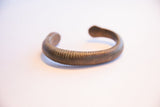 Close-up of the curved form and incised texture on the antique African bracelet.