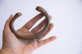 The antique African snake cuff's scale and substantial form held in hand.