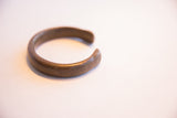 Smoothly curved antique African cuff bracelet seen from the side showing its opening.
