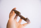 A hand holding the antique African snake cuff to demonstrate its scale and solid form.