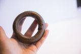 Antique African bracelet held in hand, showing the interlocking seam and surface patina.