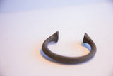 Collectible antique African manilla cuff bracelet's pointed end with rich metal patina.