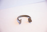 Angled profile of an antique manilla cuff showing its curved form and flared ends.