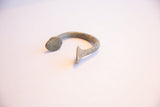 Side profile of the antique manilla cuff showing its open shape and aged, oxidized patina.