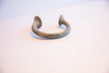 Low angle profile of the antique African cuff showing its curved form and oxidized surface.