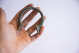 Antique African manilla cuff held in hand, displaying its unique shape and patina.