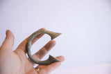 Antique manilla cuff bracelet with oxidized patina held in hand for scale.