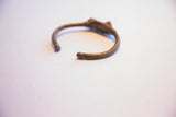The handmade curvature and open ends of a vintage African cricket cuff bracelet.