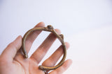 Vintage African cricket cuff bracelet held in a hand showing its form and aged patina.