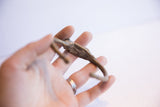 Vintage African cricket bracelet held to show its handmade form and aged patina.