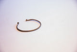 The curved form and dark, aged patina of a handmade vintage African cuff bracelet.