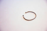 The thin, C-shaped form of a vintage African bracelet with coiled ends.