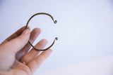 A thin vintage African cuff bracelet showing its open form and delicate, curled ends.