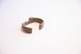 The open C-shape and aged metallic patina of a vintage African cuff bracelet.