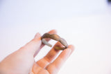 Hand holding the vintage African child's bracelet to show its wavy shape and scale.
