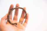 Vintage African twist cuff bracelet held in hand to demonstrate its scale.