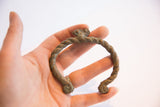 The textured, twisted band of a vintage African chameleon cuff shown in hand for scale.
