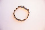 Angled view of a collectible African bracelet highlighting its handcrafted scalloped form.