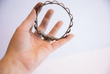 Vintage African floral bracelet showing its thin profile and handcrafted scalloped edge.