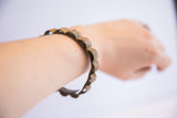 Vintage African floral design bracelet with a dark patina shown on a wrist for scale.