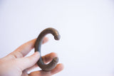 Vintage African cuff bracelet held in hand to show its C-shape and scale.